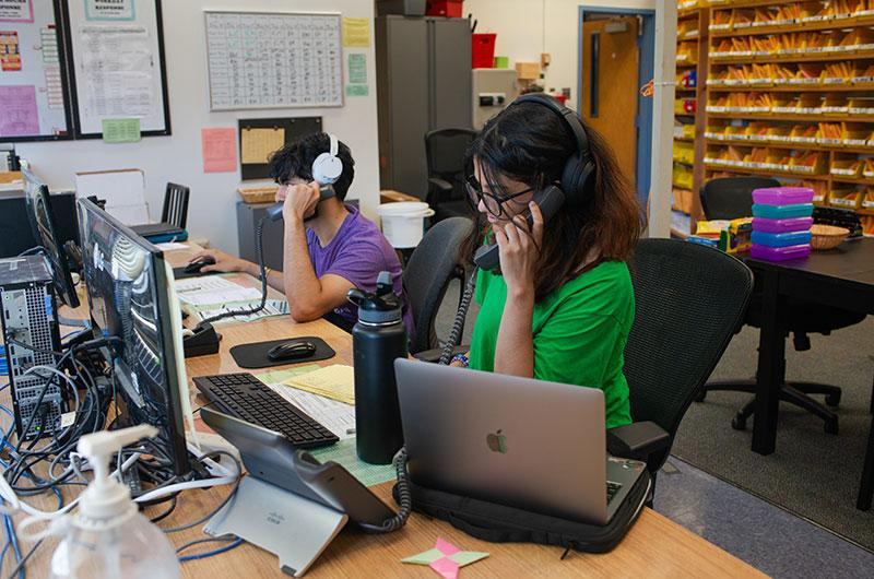 two student employees answering phone calls at the service center